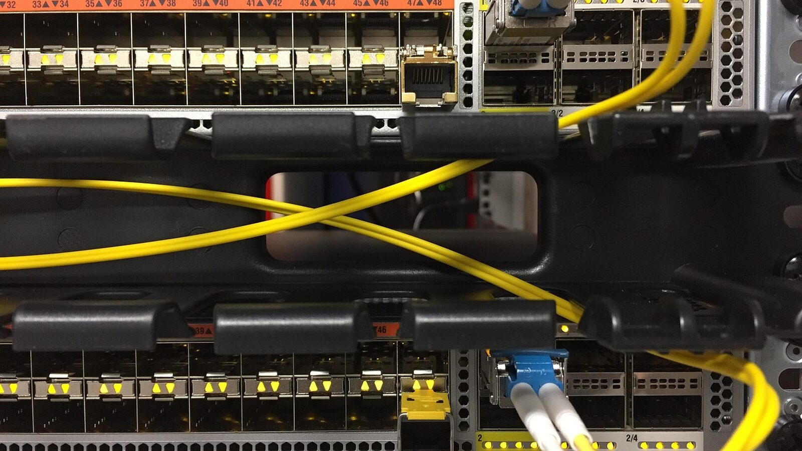 Two rack-mounted network switches with yellow fiber cables